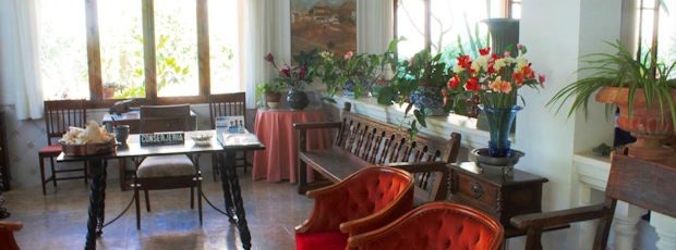 The lounge: red velvet armchairs, vases of cut flowers, and the reception table beyond by the bright windows.